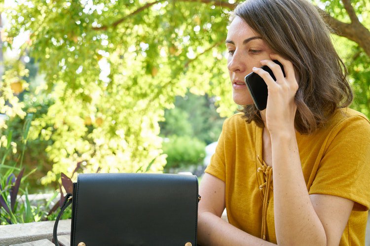 Woman making phone call while sitting at outdoor park bench