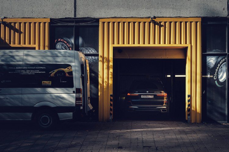 Yellow and gray commercial building with car in open garage and adjacent white service van