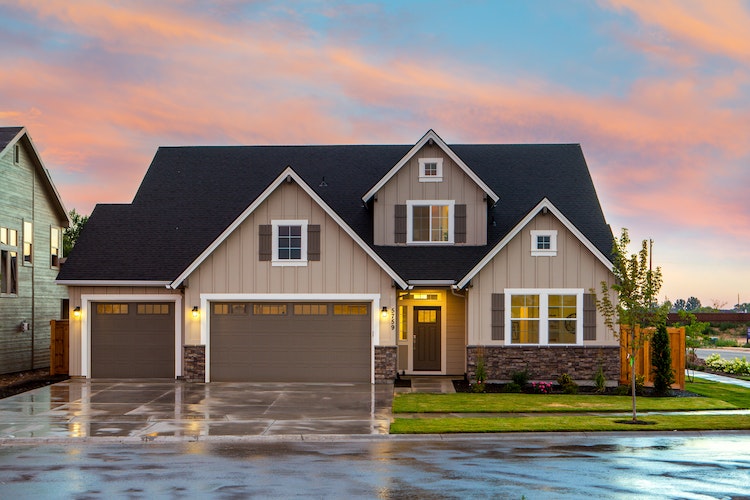 Brown and white suburban home with three-car garage at sunset