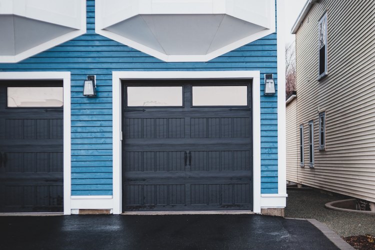 Black paneled garage doors with windows on two-car residential garage